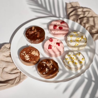 Hindistan cevizli mini tartlar, ahududu, süt, çikolata. Parlak bir arka planda gölgeli lezzetli ve renkli tatlılar. Tatlı yemek..