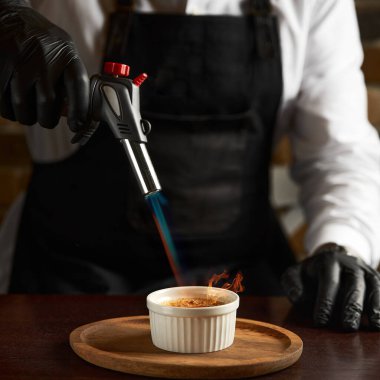 Creme brulee lehim lambası ile kovuldu. Vanilya kremasının yüzeyinde seçici bir odak noktasıyla yanmış şeker.