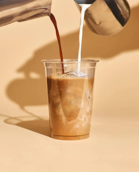 Kafenin içindeki plastik bardakta buzlu kahve sütü modeli, içkinin dokusunu ve ferahlatıcı bakışını temiz bir arka planda gösteriyor..