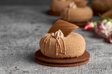 Gri arka planda çikolata kadifesi kaplı mini kremalı pasta tatlısı. Modern Avrupa pastası. Fransız mutfağı.