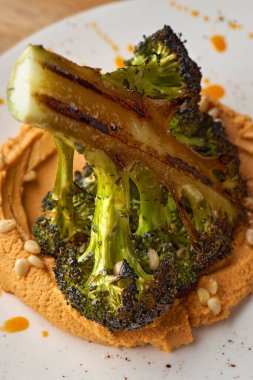 Tahta arka planda limonlu ızgara brokoli ve humus..