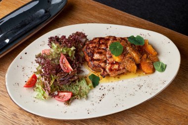 Turuncu hardallı ve rezeneli domuz boynu. Beyaz tabakta ızgara domuz bifteği ve domuz budu. Uzayı kopyala, Seçici odak. Sağlıklı konsept