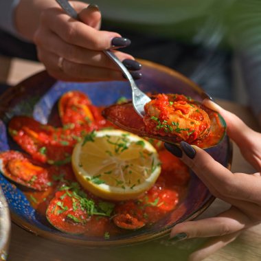 Domates soslu midyeler, kadın eli midye, yakın çekim.