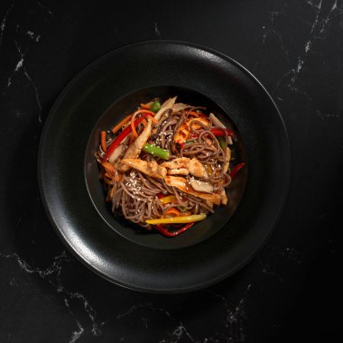 Üst manzara, Soba bifteği ve sebzeler, koyu taştan bir arka planda karabuğday eriştesi. Asya mutfağı, Wok menüsü. Geleneksel Asya yemekleri