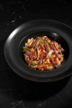 Koyu taştan bir arka planda sığır eti ve sebzeli Çin pirinci. Asya mutfağı, Wok menüsü. Yukarıdan dikey üst görünüm, Üst görünüm