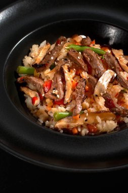 Koyu taştan bir arka planda sığır eti ve sebzeli Çin pirinci. Asya mutfağı, Wok menüsü. Yukarıdan dikey üst görünüm