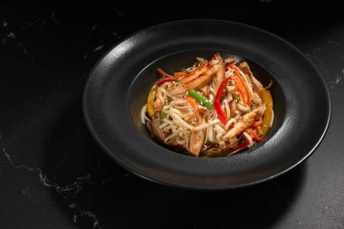 Geleneksel Asya Makarnası. Tavuk ve sebzeli udon erişteleri siyah taş arka planda bir tabakta. Düz konum, Wok menüsü. Üst görünüm