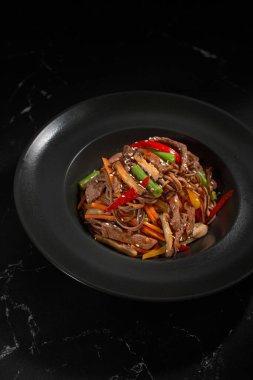 Üst manzara, Soba bifteği ve sebzeler, koyu taştan bir arka planda karabuğday eriştesi. Asya mutfağı, Wok menüsü. Geleneksel Asya yemekleri, Wok menüsü. Yukarıdan dikey üst görünüm