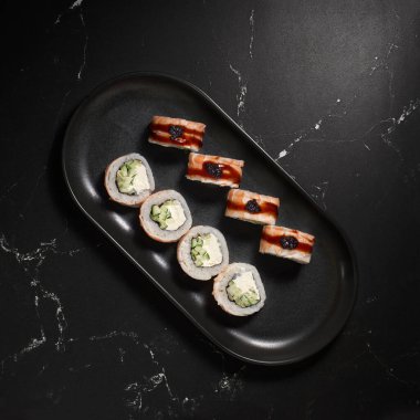 Sushi, Kanada 'yı siyah taşın üzerine yuvarladı. Seçici bir odak noktası. Japon mutfağı. - Evet. Suşi menüsü.