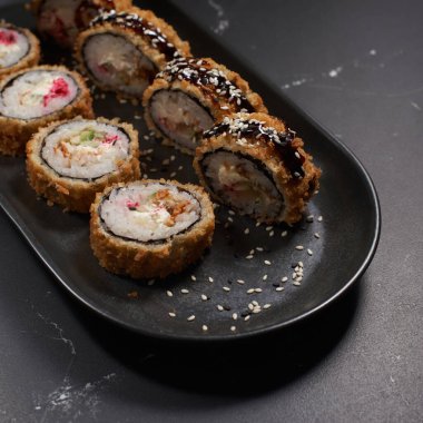 Yılan balığı ve karidesli Tempura. Kızarmış karides, yılan balığı, kaymak peyniri ve siyah desenli arka planda salatalık. Suşi menüsü. Japon yemeği..