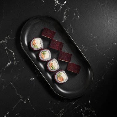 Siyah desenli arka planda yengeç eti, avokado ve masago havyarlı California suşi rulosu. Suşi menüsü. Japon yemeği. Düz yatış, Üst Görünüm