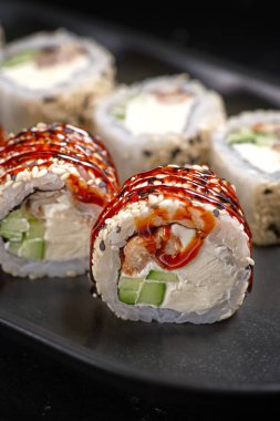 Kanada Roll, siyah desenli arka planda peynirli krema ve salatalıklı. Suşi menüsü. Japon yemeği. Yukarıdan dikey üst görünümü kapat