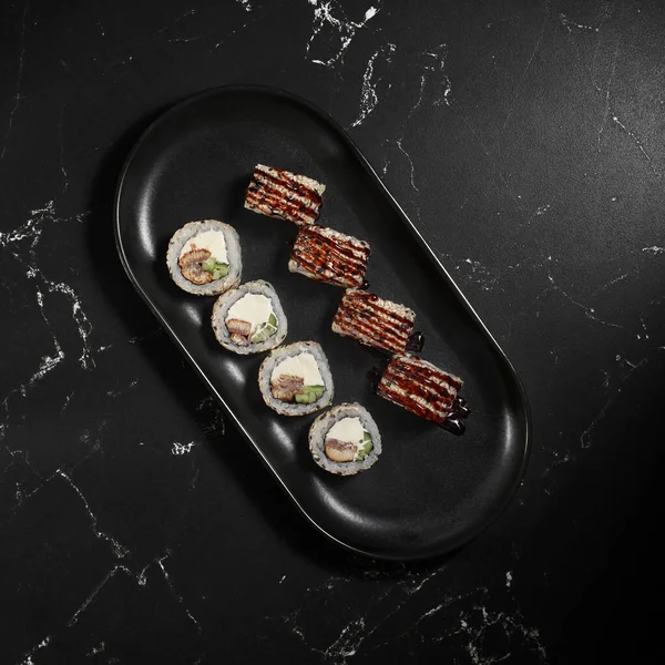 Sushi, Kanada 'yı siyah taşın üzerine yuvarladı. Seçici bir odak noktası. Japon mutfağı. Suşi menüsü. Üst görünüm
