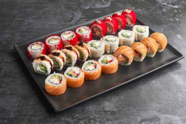 Sushi set. Roll Philadelphia, Tempura Salmon, California Red with fresh ingredients on stone background. Sushi menu. Japanese food.