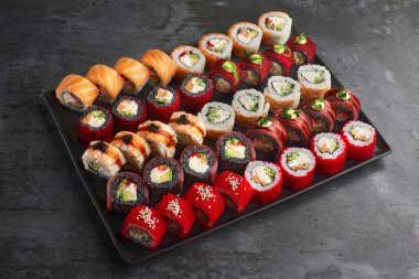 Suşi seti. Philadelphia 'yı, Tempura Ebi' yi, California Red 'i, Tempura Somon' u, Green Dragon 'u taş zeminde taze malzemelerle yuvarlayın. Sushi menüsü. Japon yemeği..