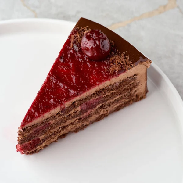 Chocolate mousse cake with dark cherries on a white plate. Close up. Selective focus, menu