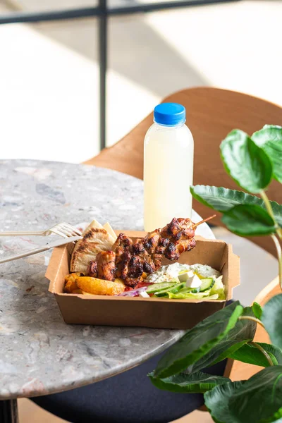 Fast food delivery.Greek souvlaki,salad and gyros take away menu from fastfood restaurant served in recyclable paper plates on table.