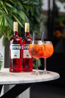 Chisinau, MOLDOVA - 12 Ağustos 2022: Bir şişe CAMPARI, soğuk Aperol spritz yaz kokteyli şarap kadehinde servis edildi. İçki ve konukseverlik kavramı. Seçici odaklı dikey resim