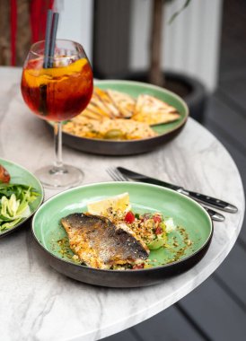 Yaz terasında yemek, ızgara levrek fileto ve humus. Seçici odaklı dikey resim.