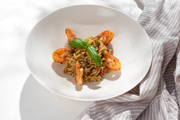 Orzo pasta with shrimps on white background for restaurant menu. Copy space