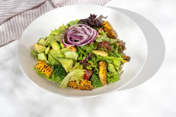 Healthy food Salad with edamame and avocado vegetables, edamame beans, bell peppers, corn, cucumbers, tomatoes, red onions on white background for restaurant menu.