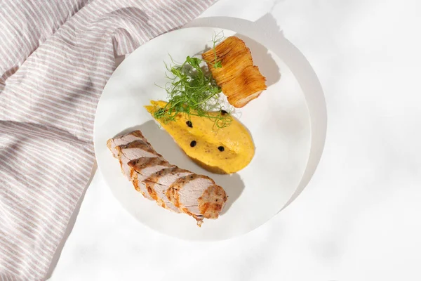 Pork tenderloin with baked potato pave on a white plate. Copy space,Selective focus. Healthy concept, menu. flat lay