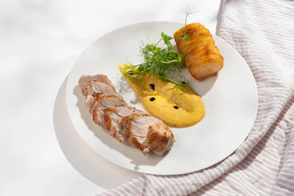Pork tenderloin with baked potato pave on a white plate. Copy space,Selective focus. Healthy concept, menu.