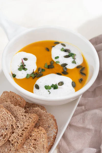 Sweet pumpkin puree vegetable soup with coconut cream on on white background. Selective focus. Healthy concept, menu.