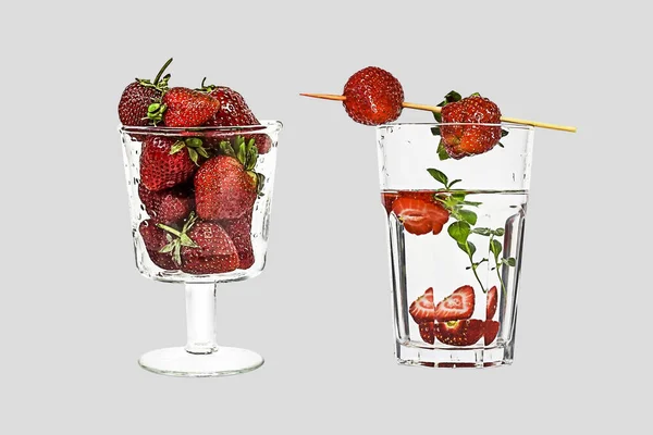 Two glasses with strawberries. Few strawberries in glass cup and home drink with strawberries and mint isolated on grey.