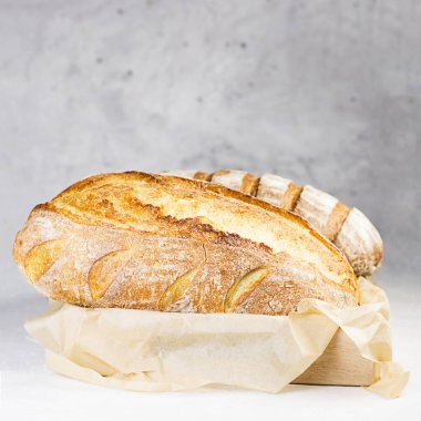 Gri arka planda el işi kağıdında taze pişmiş geleneksel ekmek. Seçici odak.