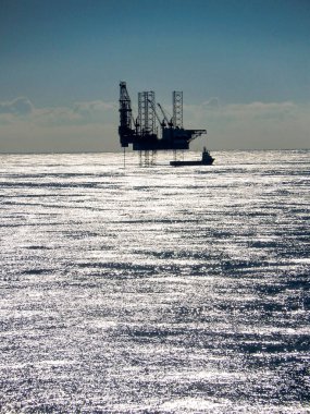 Kuzey Denizi, Avrupa - Ağustos 2014: Petrol platformu sondaj platformu, deniz yüzeyinde parlayan güneşli mavi bir gökyüzüne karşı siluetlendi