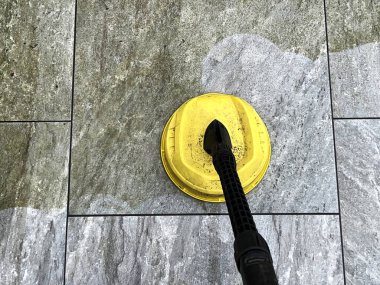 Bahçe avlusundaki porselen kaldırım levhalarının kirini ve kirini temizlemek için basınç makinası kullanılıyor. Kimse yok..