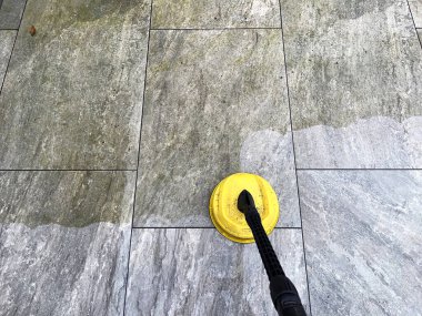 Bahçe avlusundaki porselen kaldırım levhalarının kirini ve kirini temizlemek için basınç makinası kullanılıyor. Kimse yok..