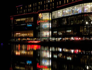 Birmingham, İngiltere - Kasım 2021: Gece yarısı Birmingham Ulusal Sergi Merkezi 'ndeki Resorts World Entertainment' in dışı. Işıklar binanın önündeki gölde yankılanıyor..