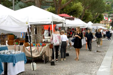 Menaggio, Como Gölü, İtalya - Haziran 2019: Como Gölü 'ndeki Menaggio kasabasındaki bir pazarda yürüyen insanlar.