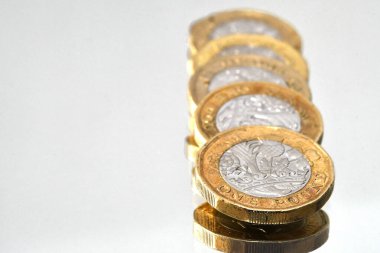 Beyaz arka planda izole edilmiş 1 poundluk madeni paraların olduğu sütunu kapat. İnsan yok. Boşluğu kopyala.