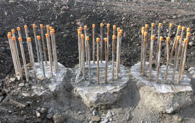 İnşaat alanındaki beton temellerden çıkan çelik çubuklar. Çubukların üst kısımlarında plastik güvenlik kapakları var. Kimse yok..