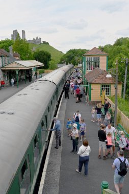 Corfe Castle, Dorset, İngiltere - Haziran 2021: İnsanlar kırsal köy tren istasyonunda trene yetişiyor