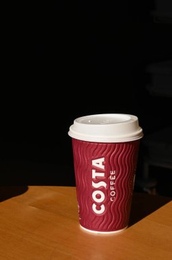 Carmarthen, Wales - Mart 2022 Costa Coffee 'nin bir şubesindeki masada duran plastik kapaklı kağıt bardak. Kimse yok..