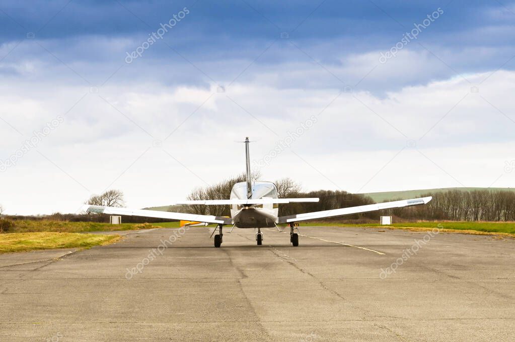 Rear view of a single engined private light aircraft taxiing for take-off. No people.