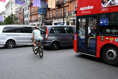 Londra, İngiltere - Ağustos 2021: Bisikletçi Londra 'nın merkezindeki bir yol kavşağında trafik sıkışıklığından zikzak çizerek geçiyor. Bisikletçi kask takmıyor..