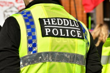 Cardiff, Wales - Mart 2022: Cardiff şehir merkezinde görevli bir polis memurunun floresan yeleğinin arka görünüşü