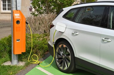 Speyer, Almanya - Nisan 2022: Elektrikli araç bir otoparkta şarj noktasına takıldı