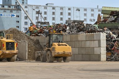 Basel, İsviçre - Nisan 2022: Mekanik kazıcı kentin rıhtım bölgesinde hurda metal geri dönüşüm sahasında çalışıyor.