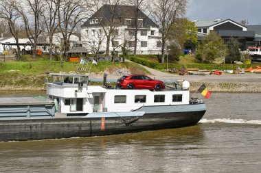 Koblenz, Almanya - Nisan 2022: Moselle Nehri 'ndeki bir sanayi mavnasının arkasındaki köprüyü kapatın. Arka güvertede kaptanın arabası var..