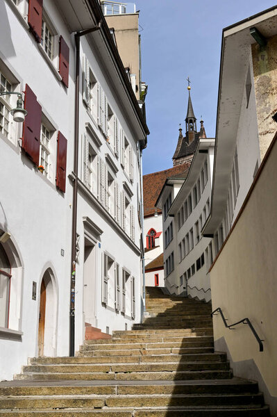 Basel, Switzerland - April 2022: Steps leading up a hill through a narrrow path between old buildings in the city centre. No people.