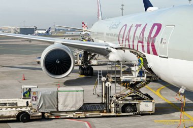 Frankfurt, Almanya - Nisan 2022: Katar Havayolları Boeing 777 jetinin yük ambarına konteynerleri yüklemek için hidrolik bir hava yükü yükleyicisi kullanan havaalanı işçisi.