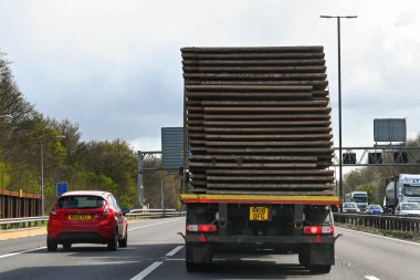 Bristol, İngiltere - Nisan 2022: M4 otoyolunda bir arabayı sollayan uzun tahta çarşaflı bir kamyonun arka görüntüsü