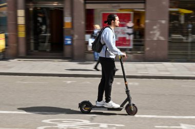 Strasbourg, Fransa - Nisan 2022: Strasbourg şehir merkezinde bir sokakta elektrikli scooter kullanan kişi