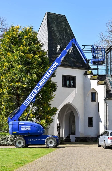 Koblenz, Germany - April 2022: Cherry picker mobile platform vehcile with hydraulic arm extended  ouytside a building